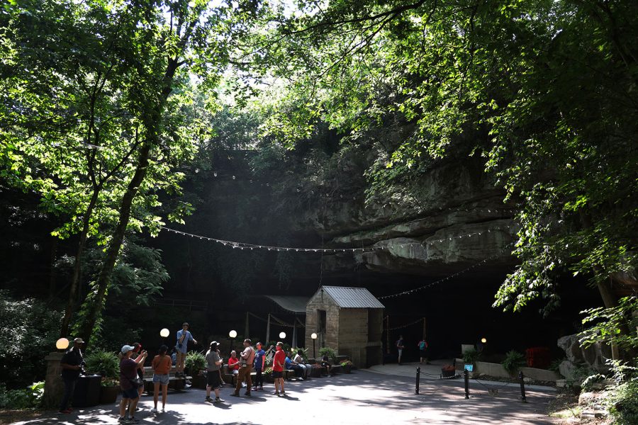 The sun shines through trees as tourists explore the entrance to Lost River Cave on June 6. Lost River Cave offers boat tours into the cave.