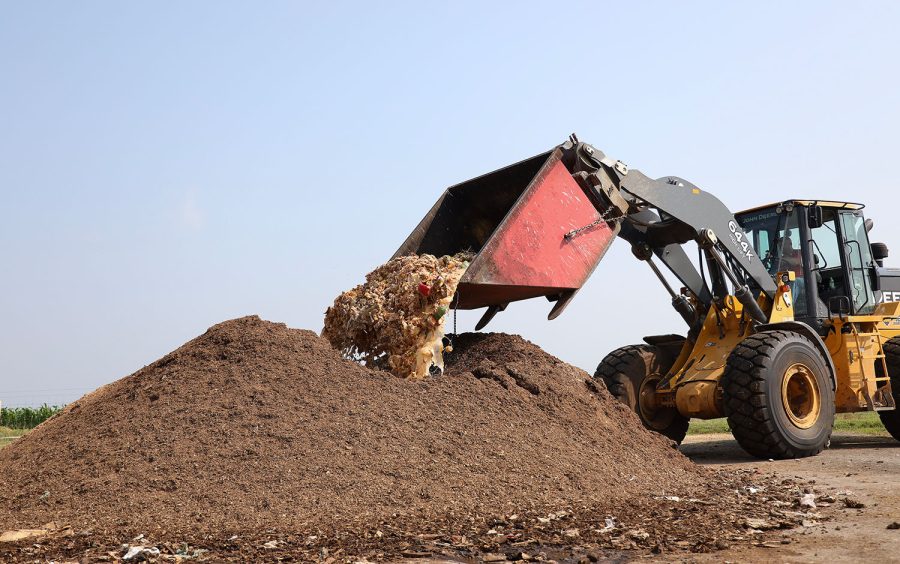 Joey Reynolds, an agriculture technician at the WKU Farm, drives a front-end loader to dump food compost into a pile of leaves. 
(Photo by David Quintanilla/ Bowling Green High School)